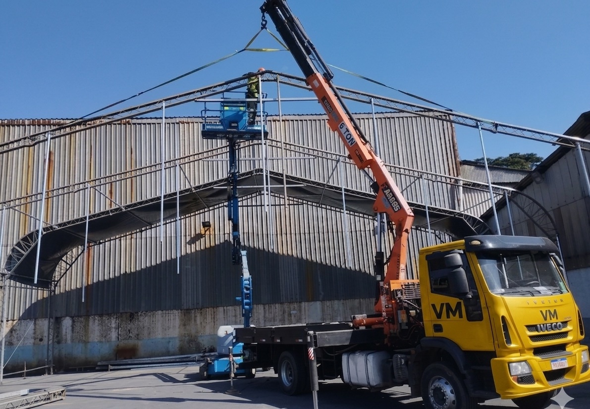 Caminhão Munck da VM montando estrutura metálica arqueada em obra industrial